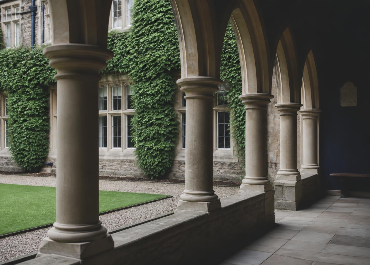 Stone cloister arches beside a lawn at a UK independent school